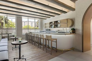 A modern bar area with a long counter, bar stools, and a seating area with a sofa and tables. - Live Oak, Charleston Historic District, a Tribute Portfolio Hotel (Charleston)