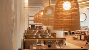 A restaurant with wicker pendant lighting, wooden tables, and a modern interior design.