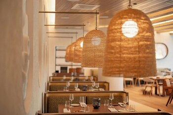 A modern reception area with a round table, two chairs, a reception desk, and a wall-mounted light fixture. at Live Oak, Charleston Historic District, a Tribute Portfolio Hotel