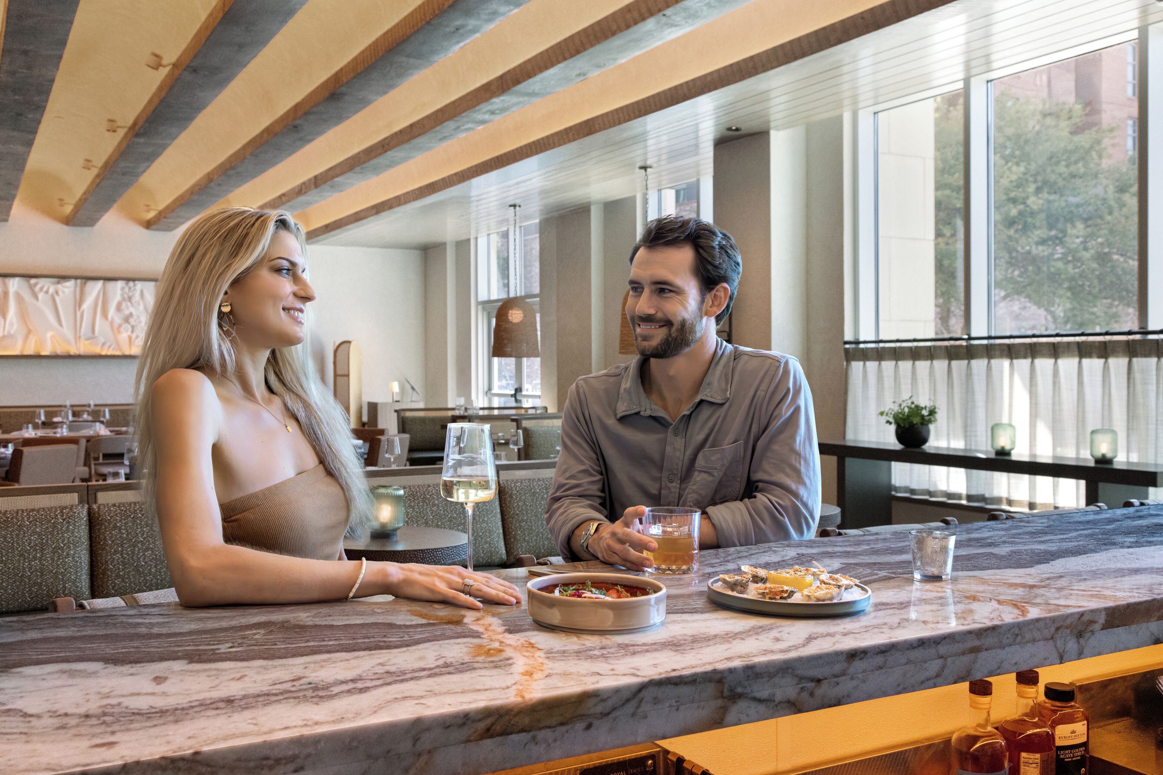 A couple dining at a marble bar with a view of the outdoors.