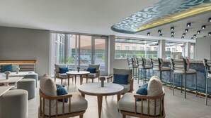 A modern lounge area with round tables, cushioned chairs, and a bar counter.