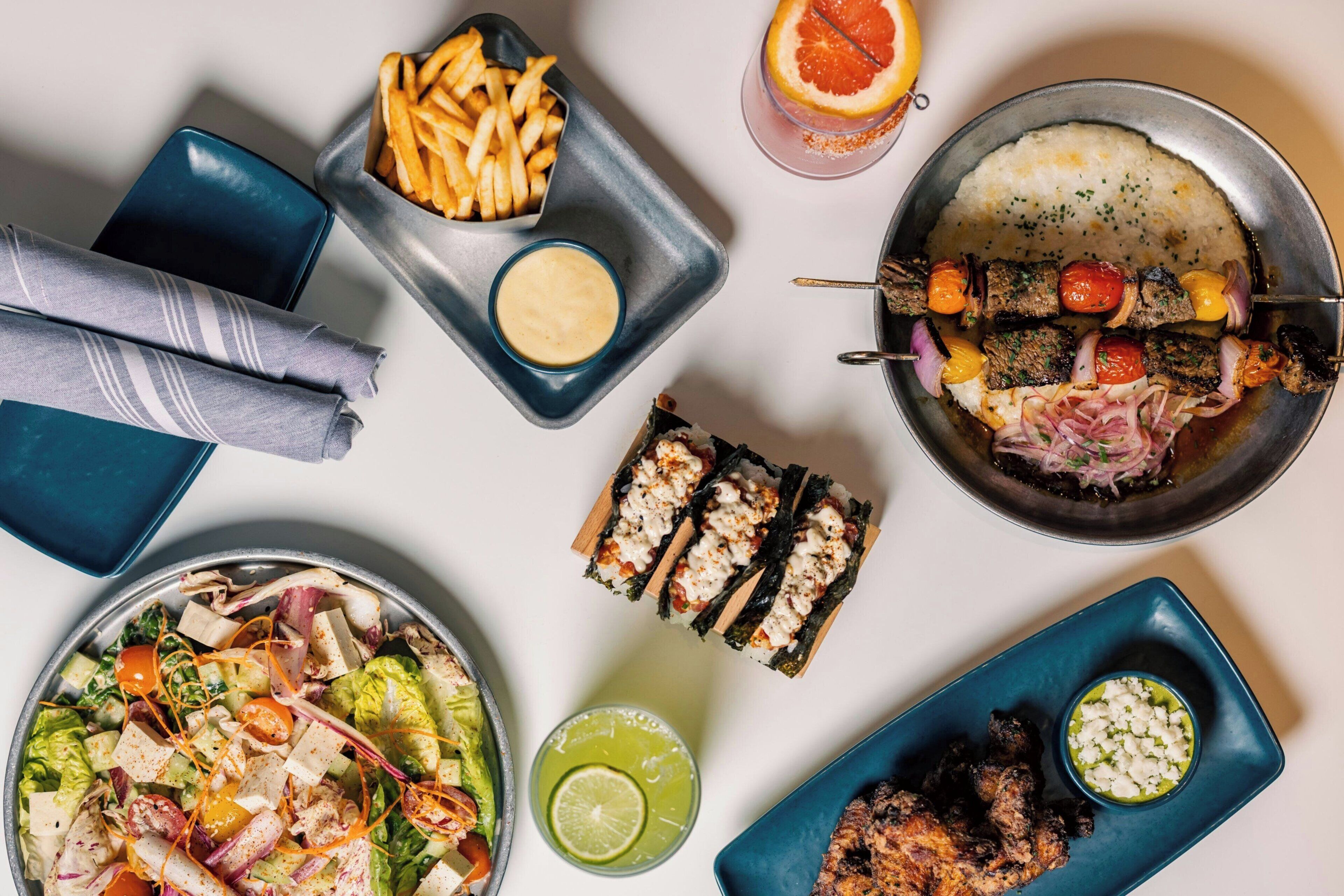 A variety of dishes including a salad, grilled meat, and sushi.