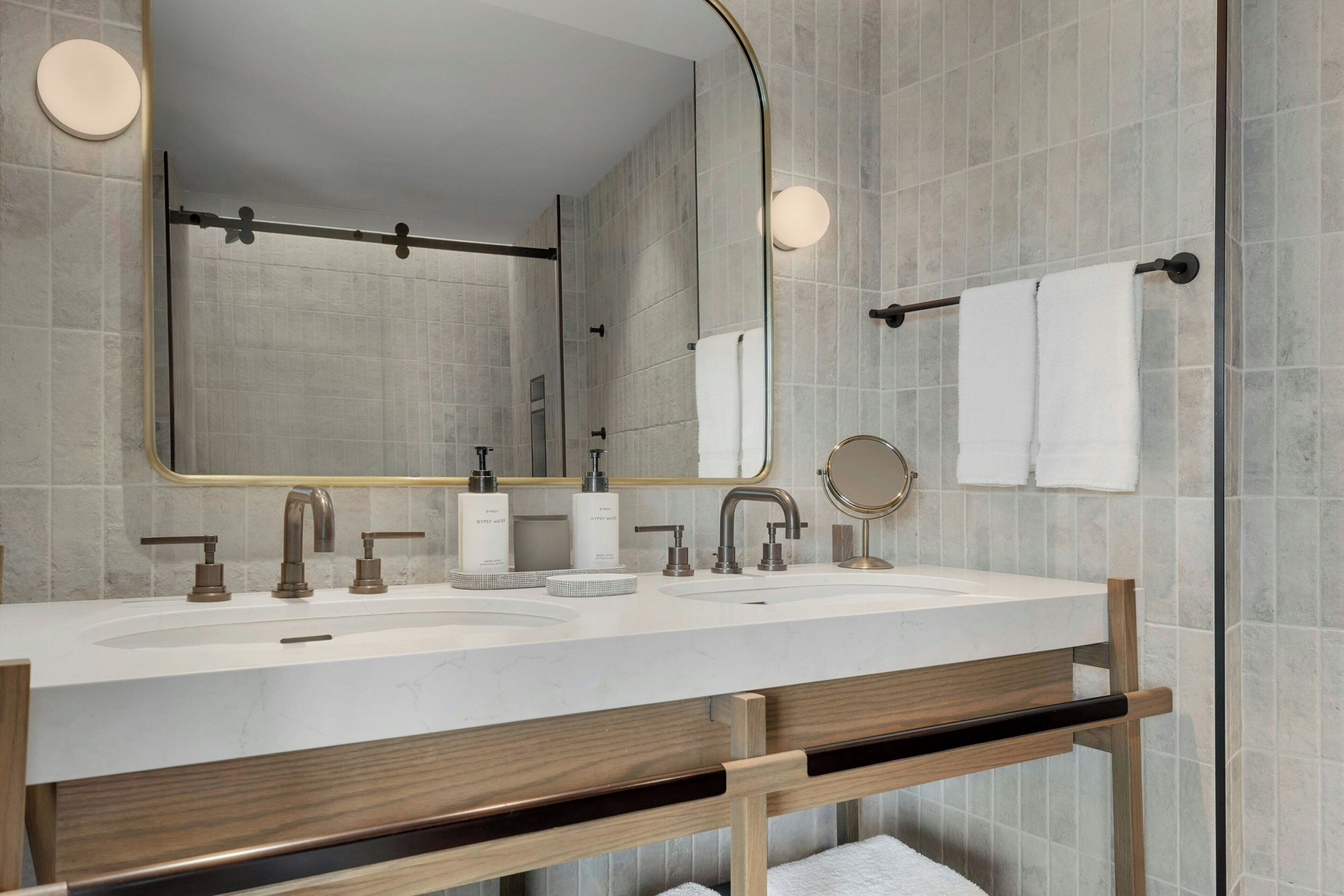 A modern bathroom with a large mirror, two sinks, and a towel rack.