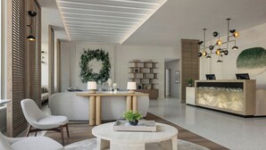 A modern reception area with a round table, two chairs, a reception desk, and a wall-mounted light fixture.