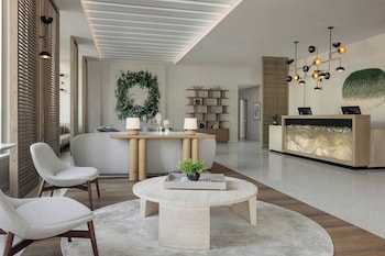 A modern lounge area with round tables, cushioned chairs, and a bar counter. at Live Oak, Charleston Historic District, a Tribute Portfolio Hotel