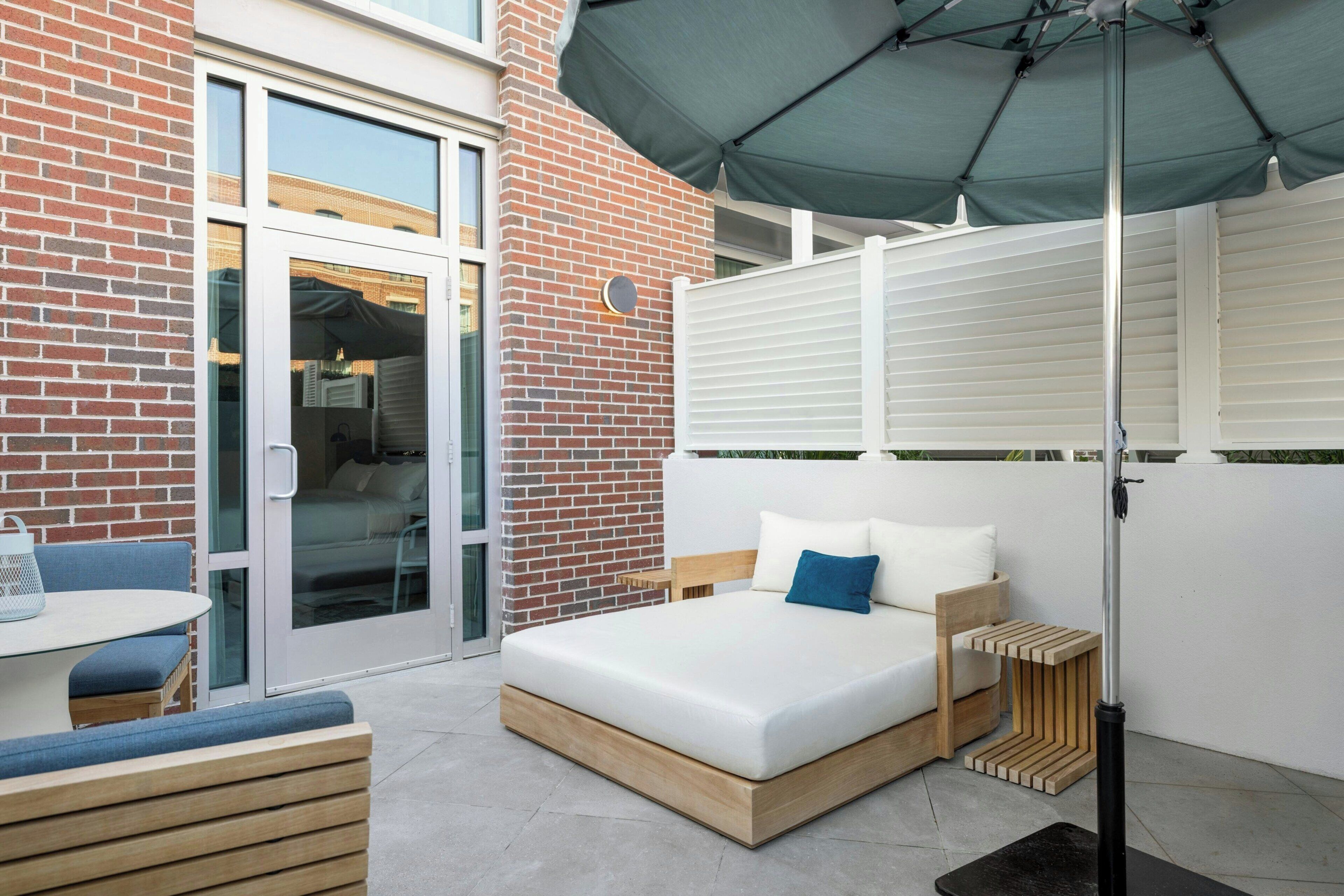 A modern outdoor bedroom with a bed, a table, and a chair.