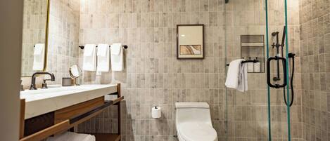 A modern bathroom with a toilet, sink, and shower area.