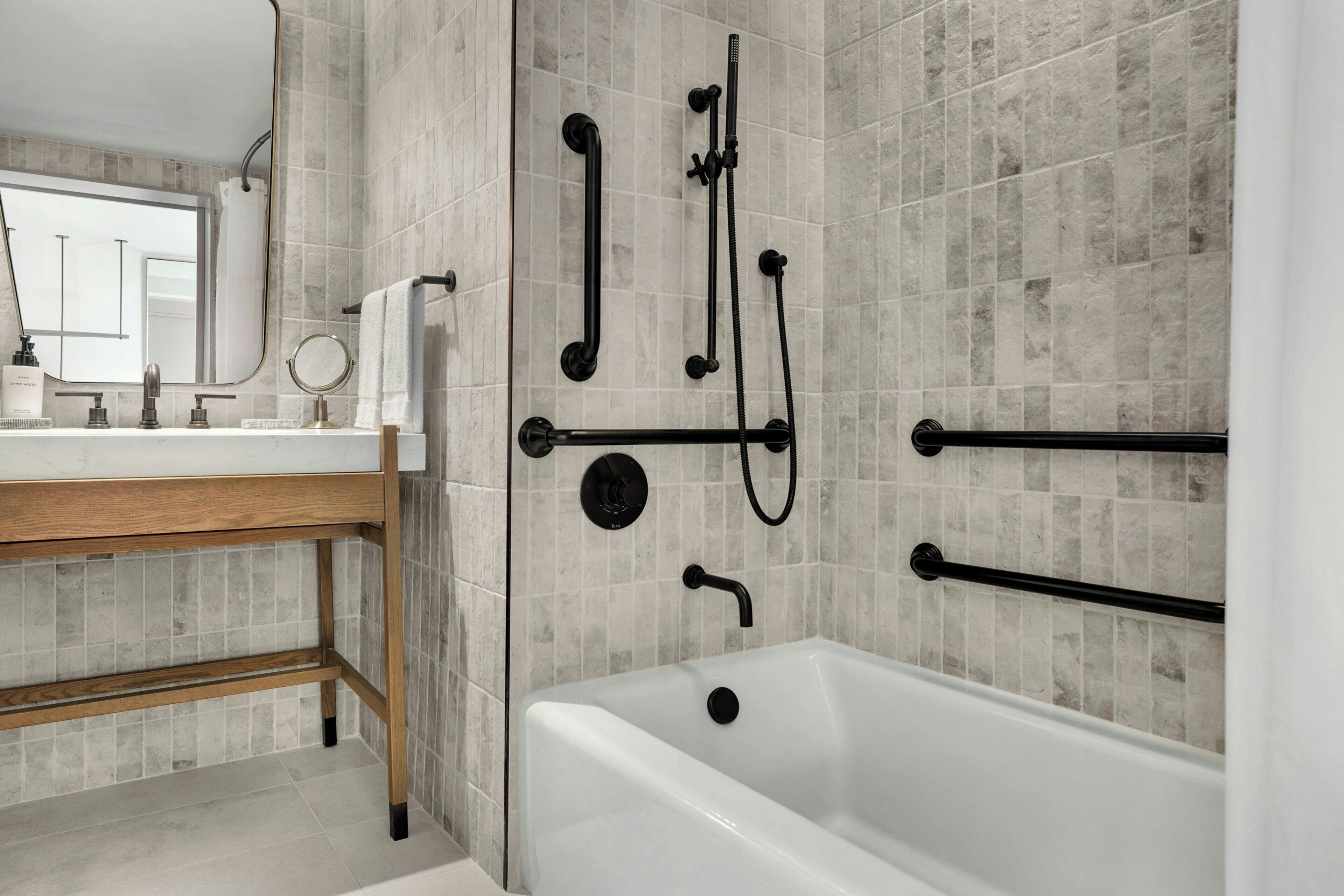 A modern bathroom with a bathtub, a vanity with a mirror, and a shower with a handheld showerhead.
