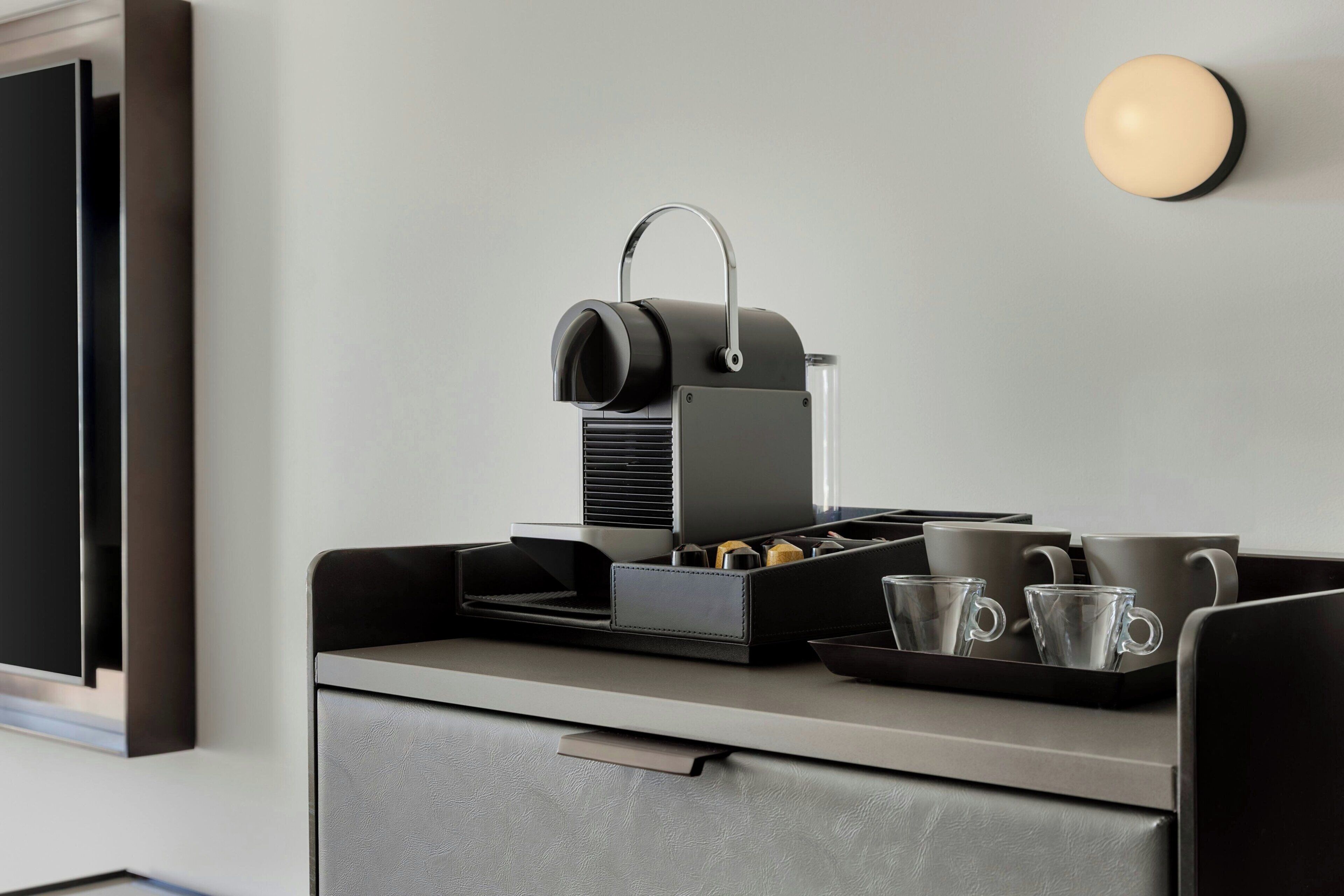 A kitchenette with a coffee machine, a tray with cups, and a drawer.