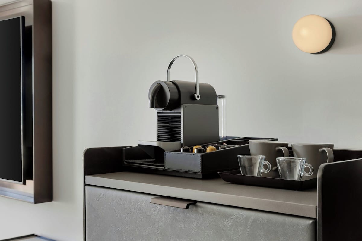 Une petite cuisine équipée d’une machine à café, d’un plateau avec des tasses et d’un tiroir.