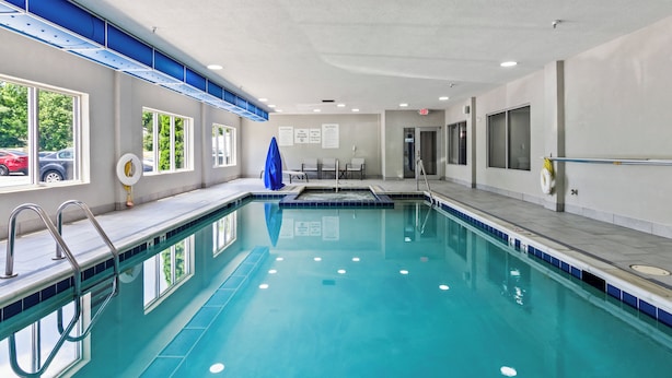 An indoor swimming pool with clear blue water, a blue and white tiled deck, and a view of parked cars outside. - Holiday Inn Express and Suites Wytheville by IHG (Wytheville)