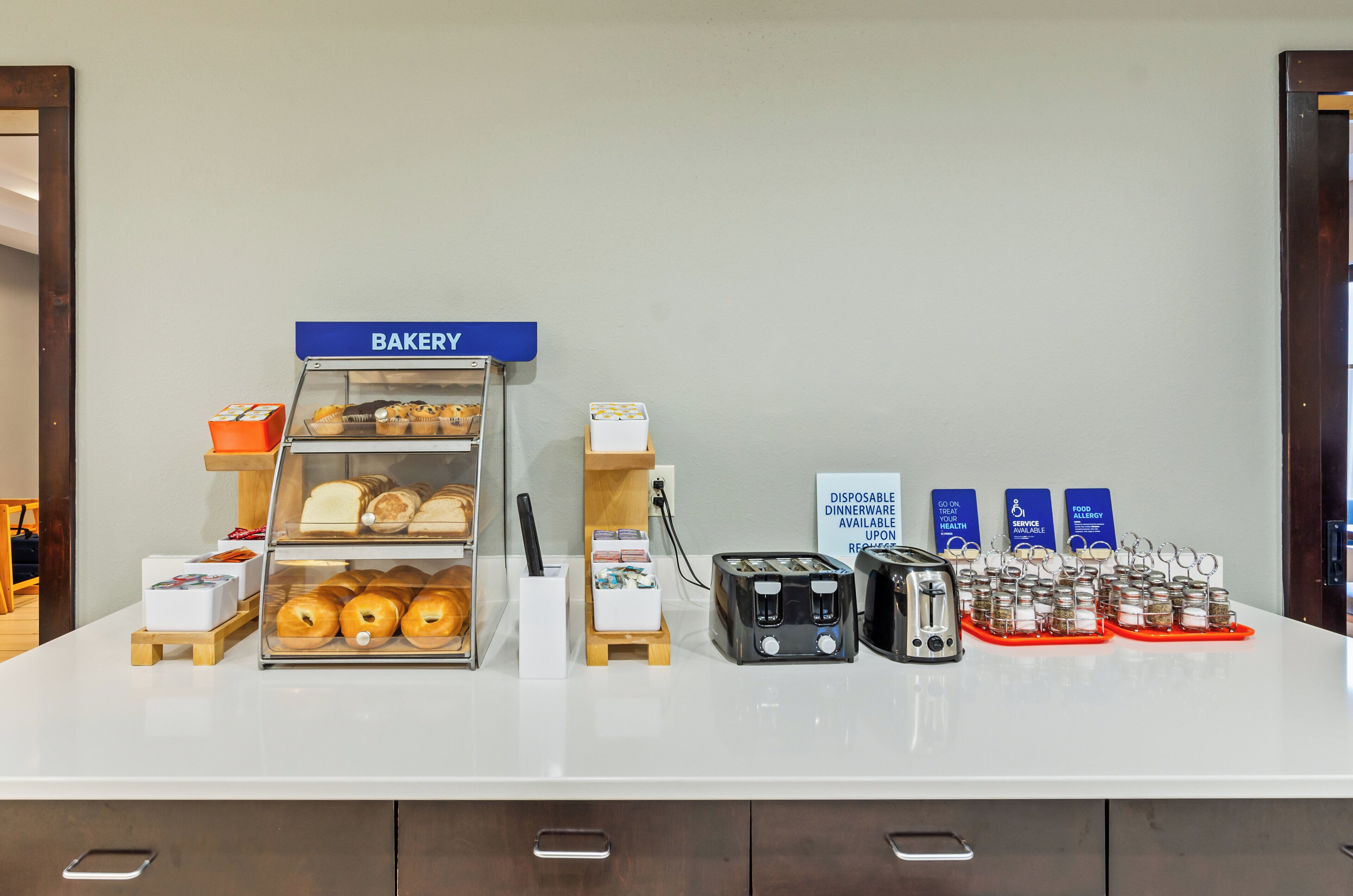 A bakery counter with various baked goods and a sign indicating disposable dinnerware is available.