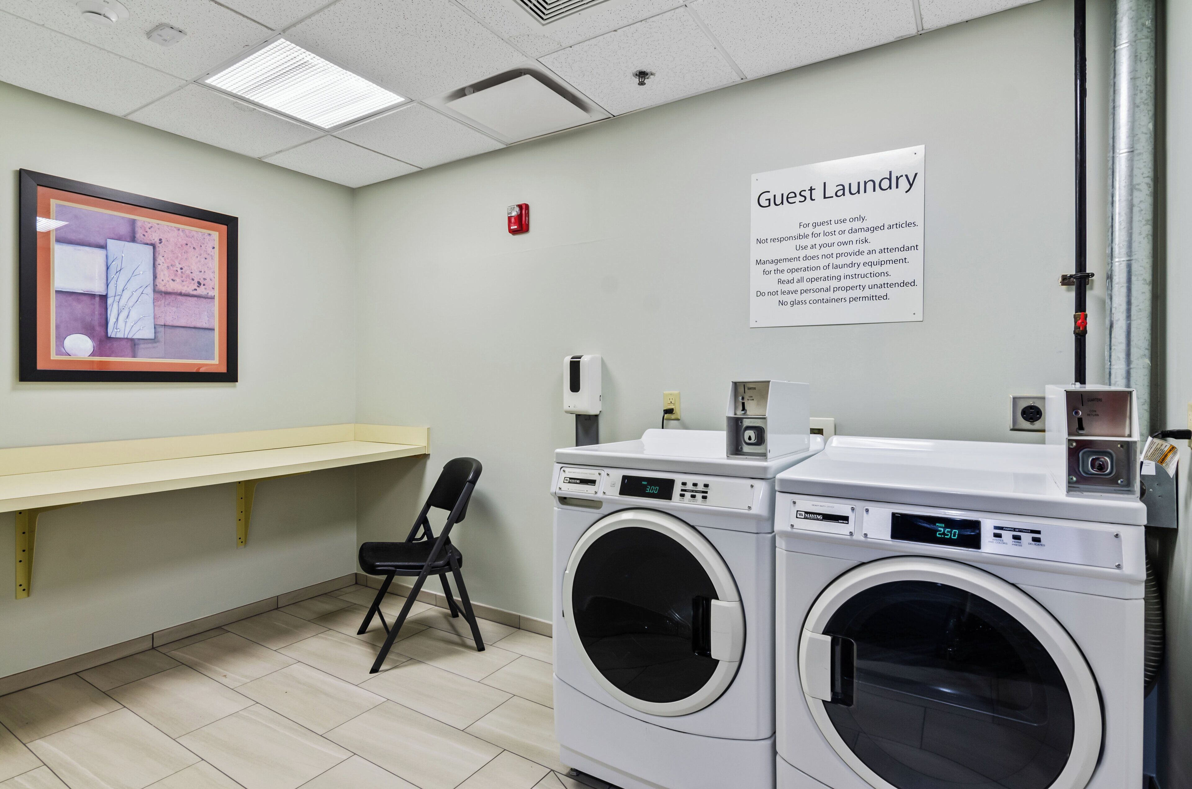 A guest laundry area with two washing machines, a chair, and a sign indicating guest-only use.