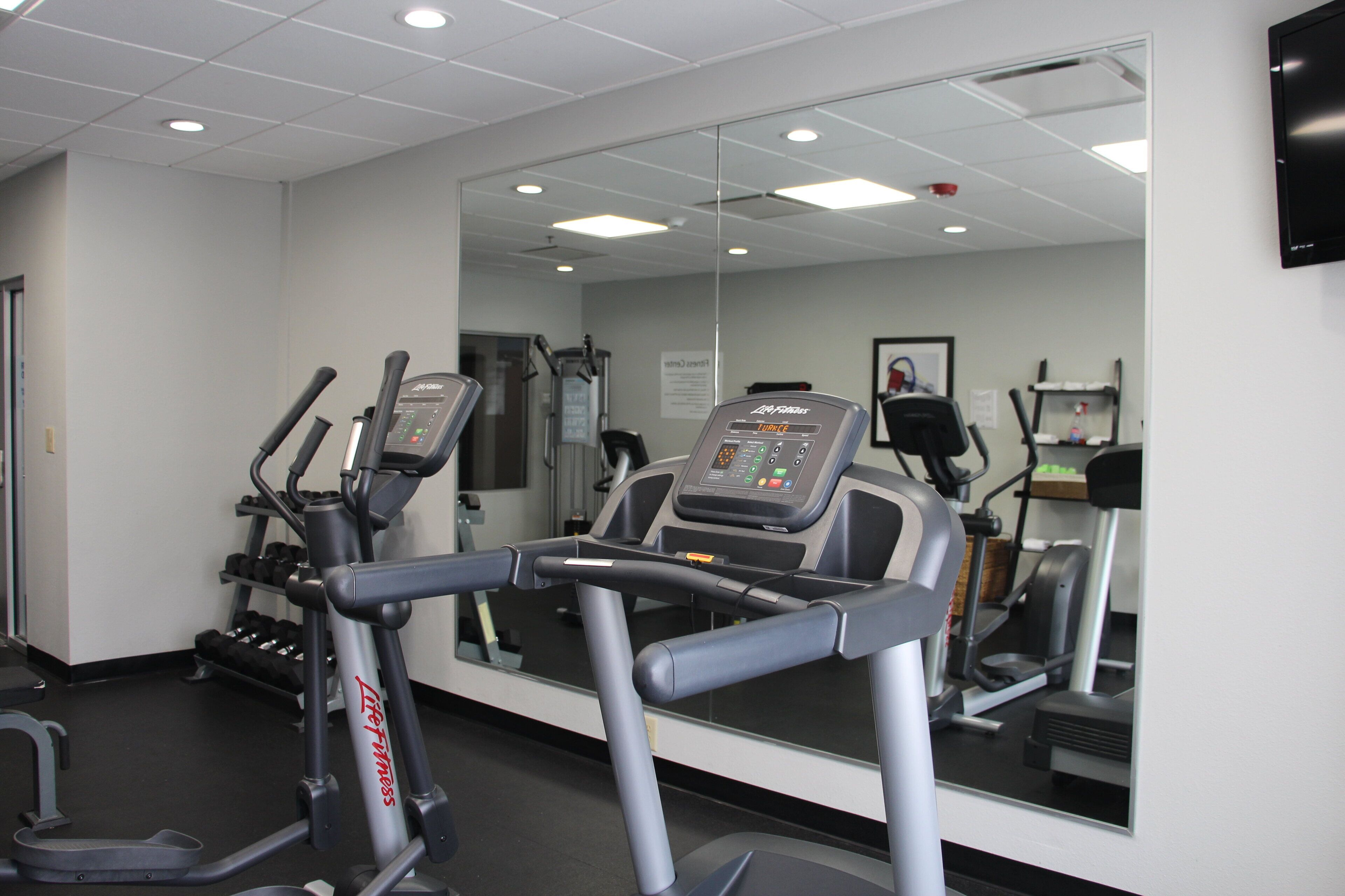 Une salle de sport équipée de tapis de course, d’haltères et d’appareils d’exercice.
