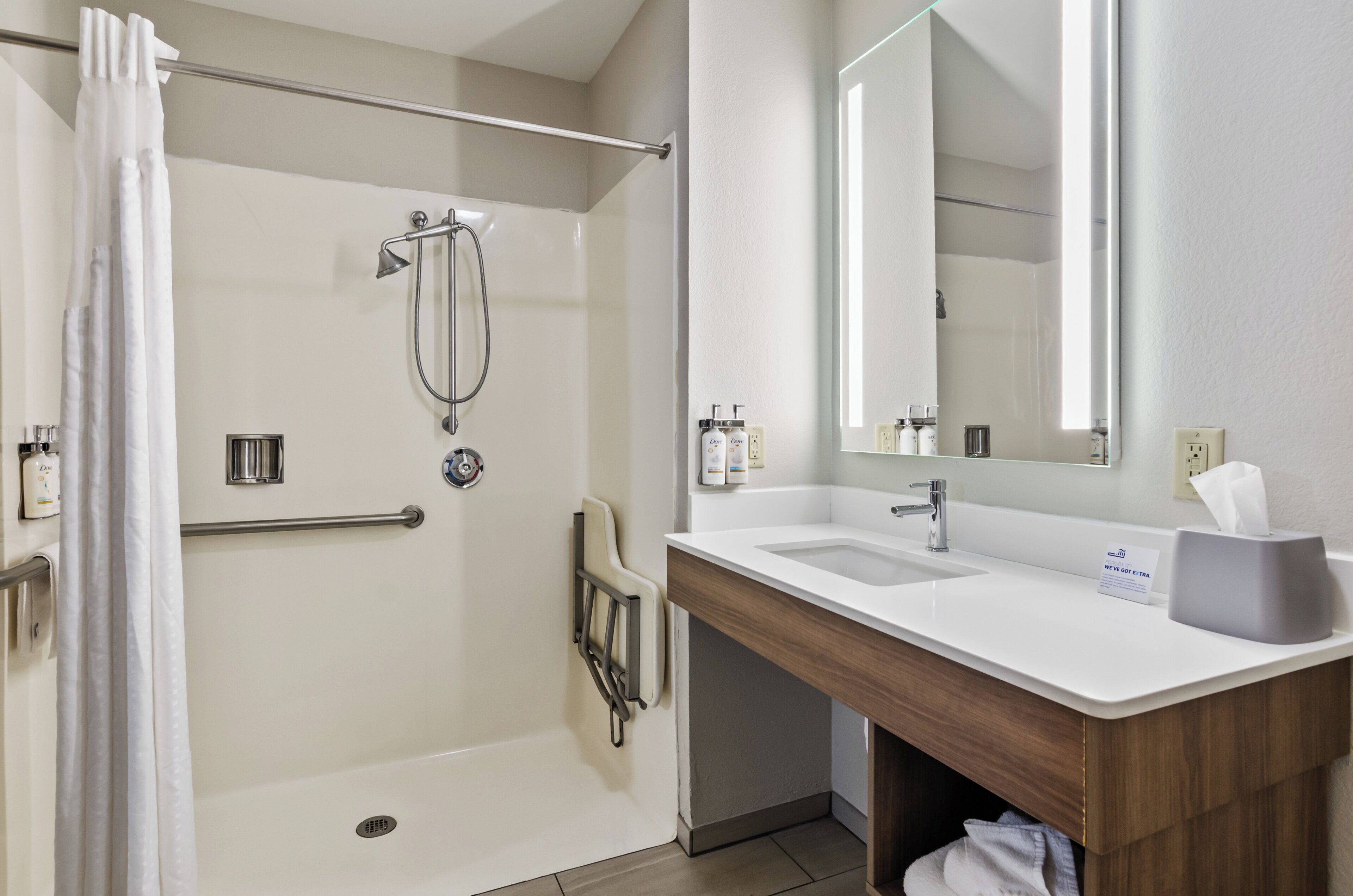 A modern bathroom with a walk-in shower, a vanity with a mirror, and a sink.