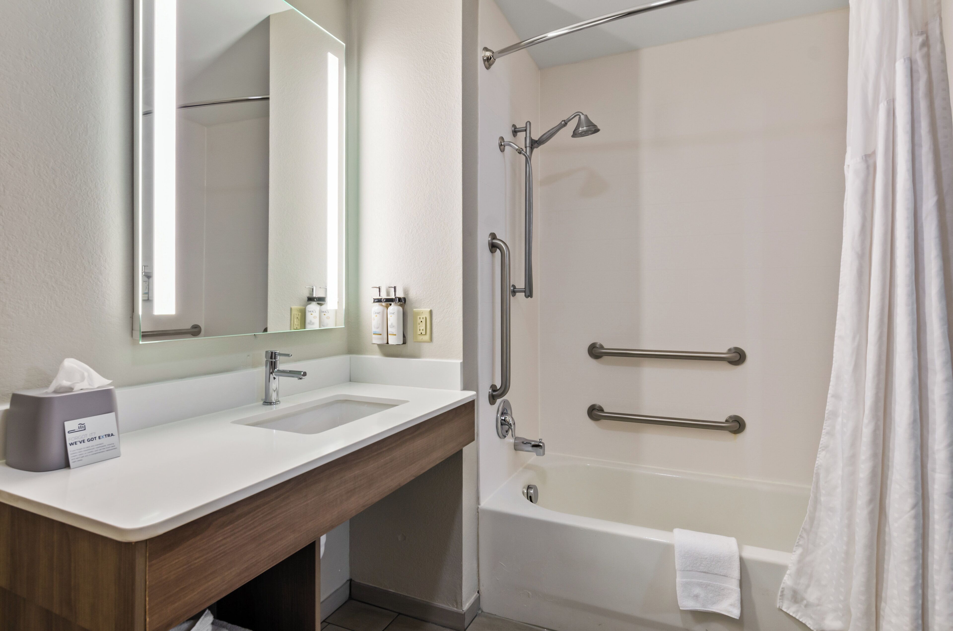 A bathroom with a sink, mirror, and shower.