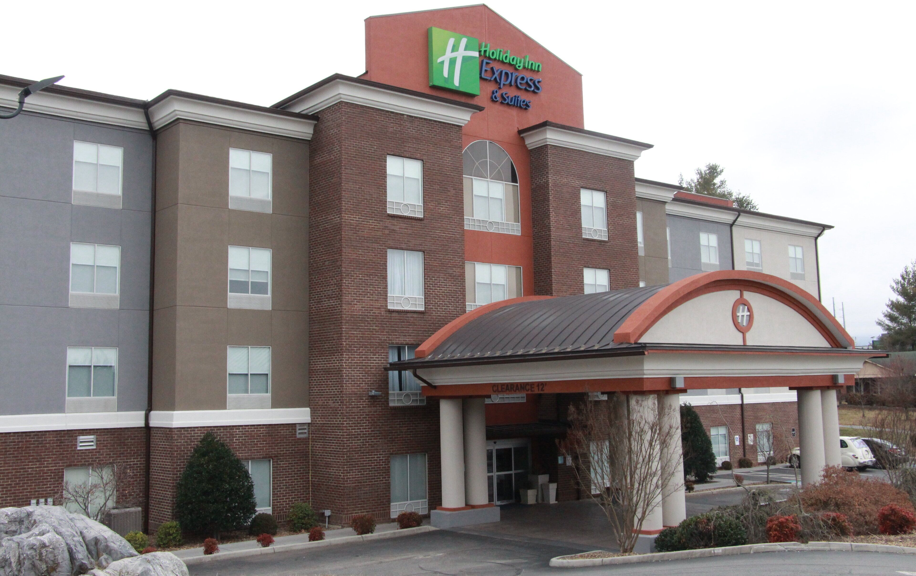 A Holiday Inn Express & Suites building with a brick facade, multiple windows, and a covered entrance.