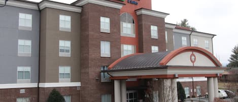 Ein Holiday Inn Express & Suites Gebäude mit Backsteinfassade, zahlreichen Fenstern und einem überdachten Eingang.