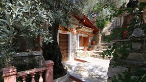 A stone pathway leading to a traditional building with a tiled roof and wooden shutters. - Villa Symbola (Fethiye)