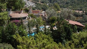 A villa with a swimming pool surrounded by dense trees and a mountainous backdrop. - Villa Symbola (Fethiye)