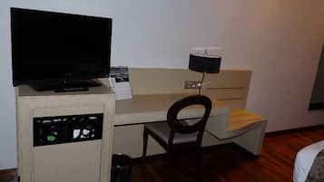 Una camera d'albergo piccola con un letto, una scrivania con un computer, una televisione e una sedia.