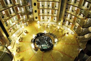 A multi-level atrium with a central circular area featuring seating and a glass floor. - Cumbria Spa&hotel (Ciudad Real)