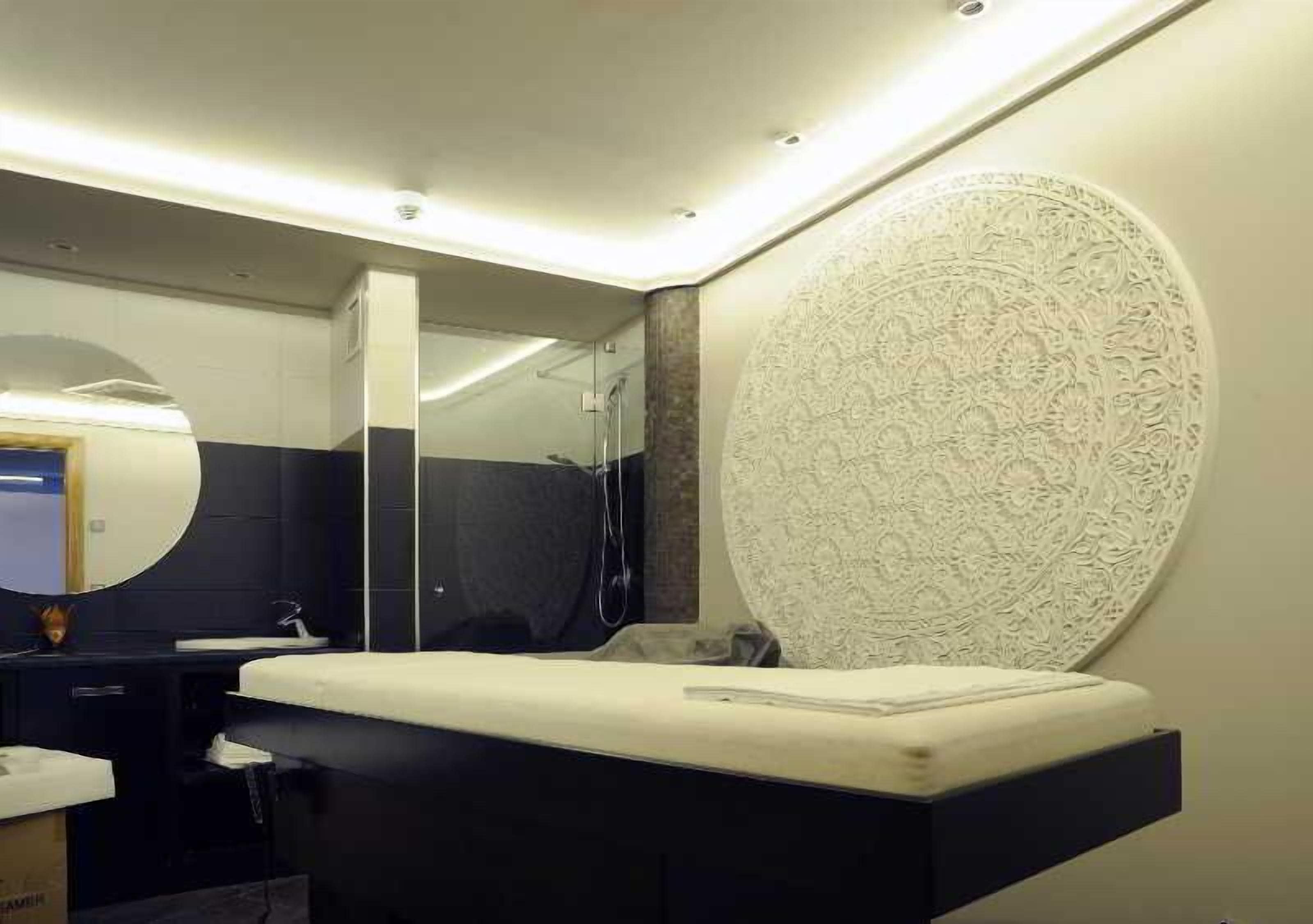 Un baño moderno con un espejo grande, un lavamanos y un panel decorativo en la pared.