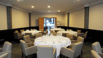 A conference room with multiple round tables set for dining, equipped with chairs and table settings.