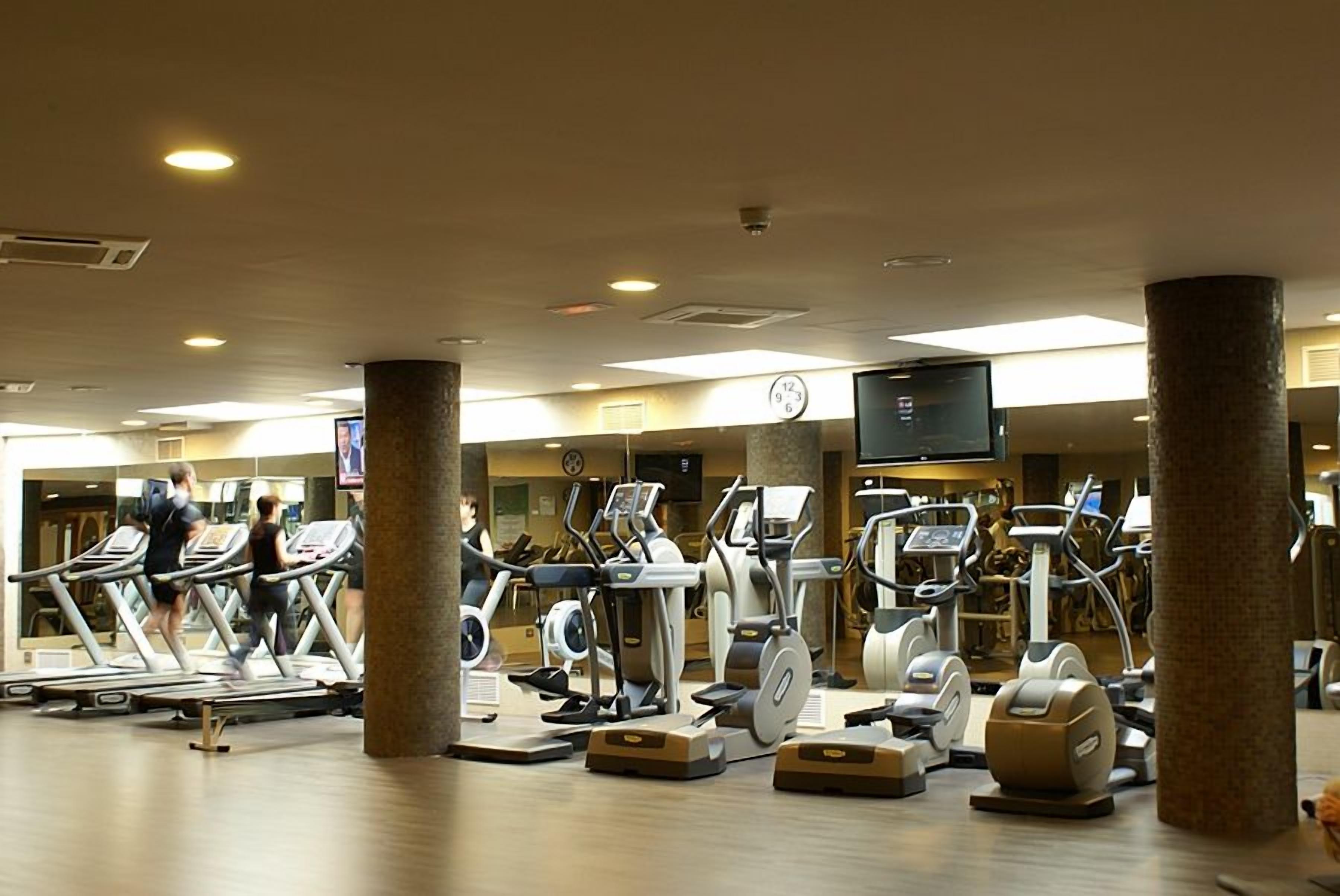 Un gimnasio con cintas de correr, elípticas y bicicletas estáticas.