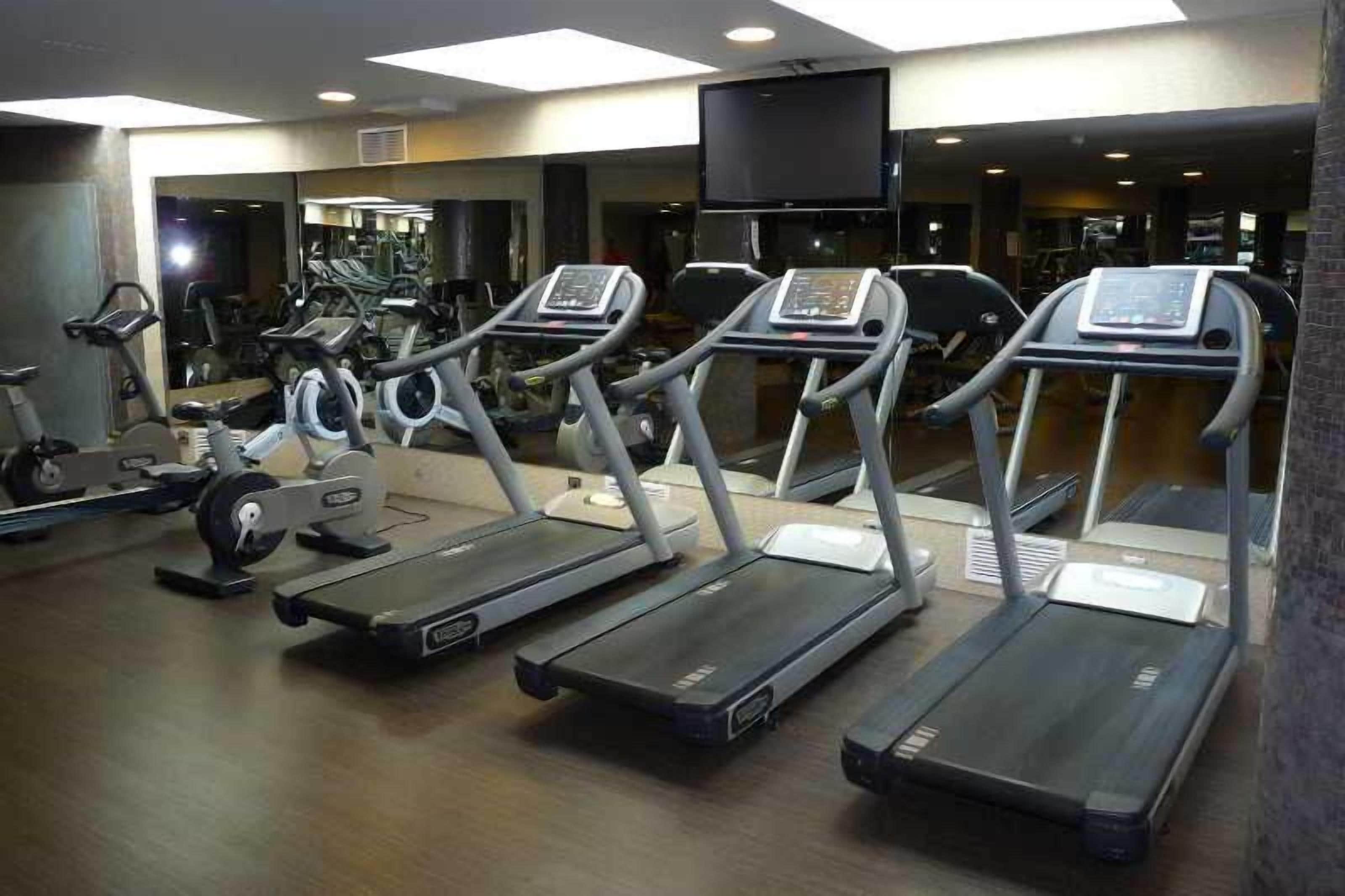 Un gimnasio con cintas de correr, bicicletas estáticas y máquinas de pesas.