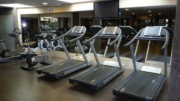 Un gimnasio con cintas de correr, bicicletas estáticas y máquinas de pesas.