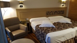 A hotel room with a bed, a chair, a bedside table, and a lamp. - Cumbria Spa&hotel (Ciudad Real)