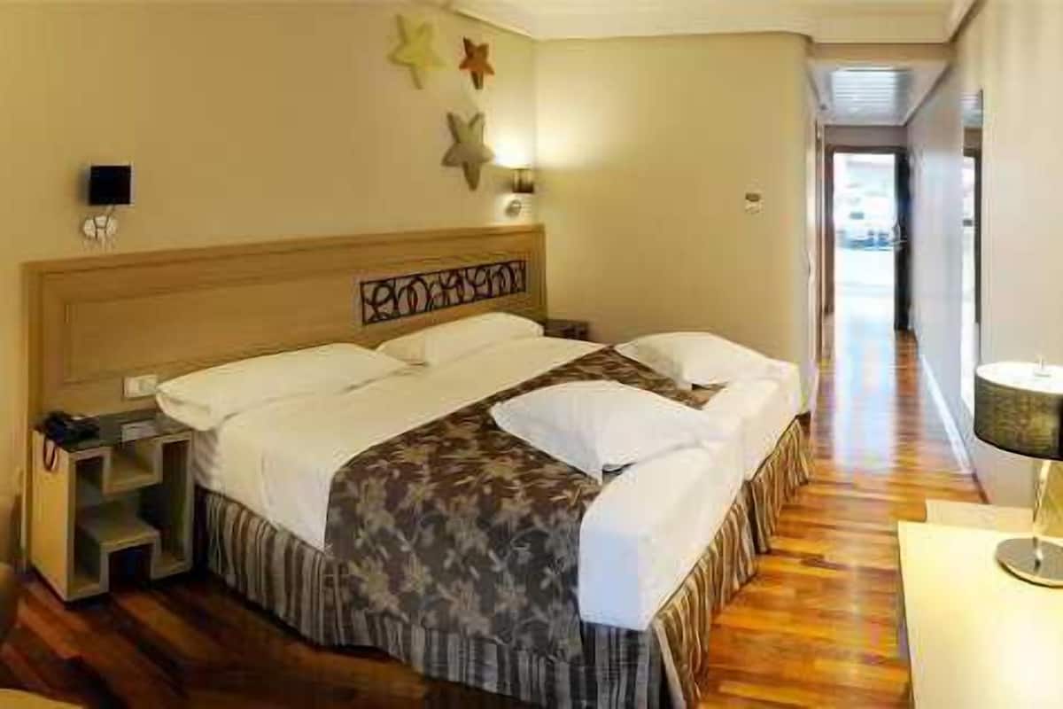 Ett hotellrum med en säng, en stol, ett skrivbord och en lampa.