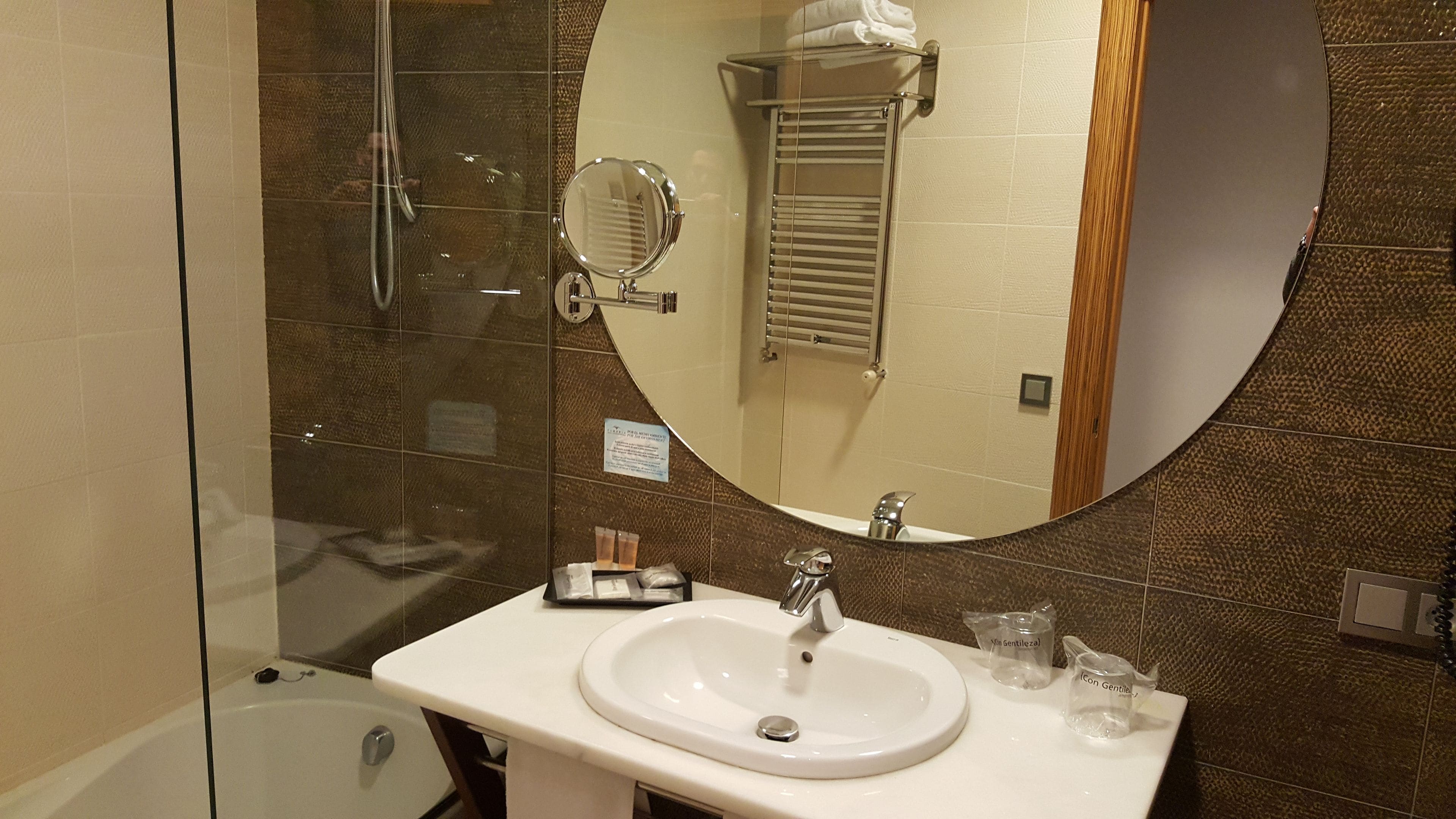 Une salle de bain avec un lavabo blanc, un miroir et une cabine de douche en verre.