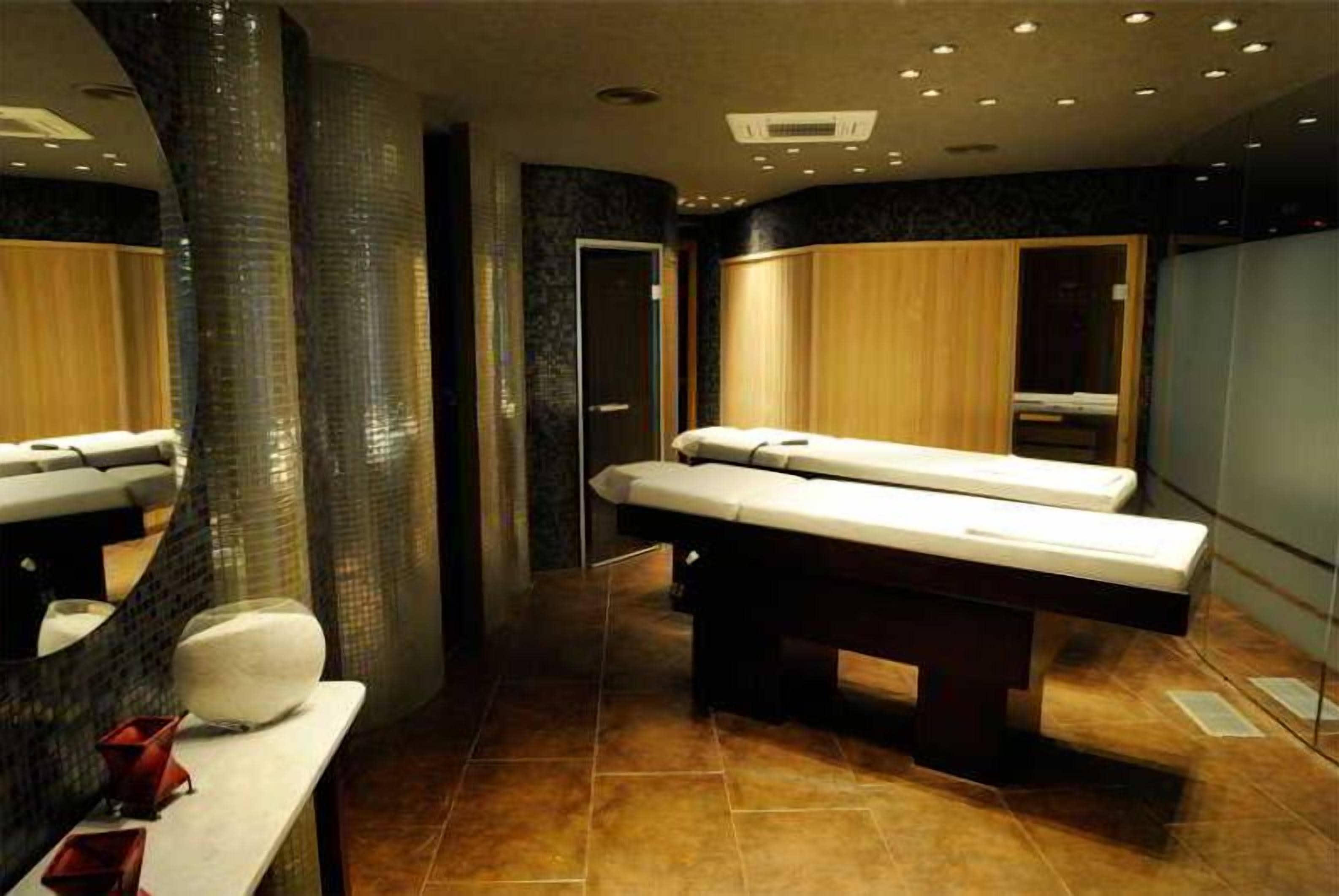 Un moderno spa con una camilla de masaje, un espejo grande y un mueble de madera.