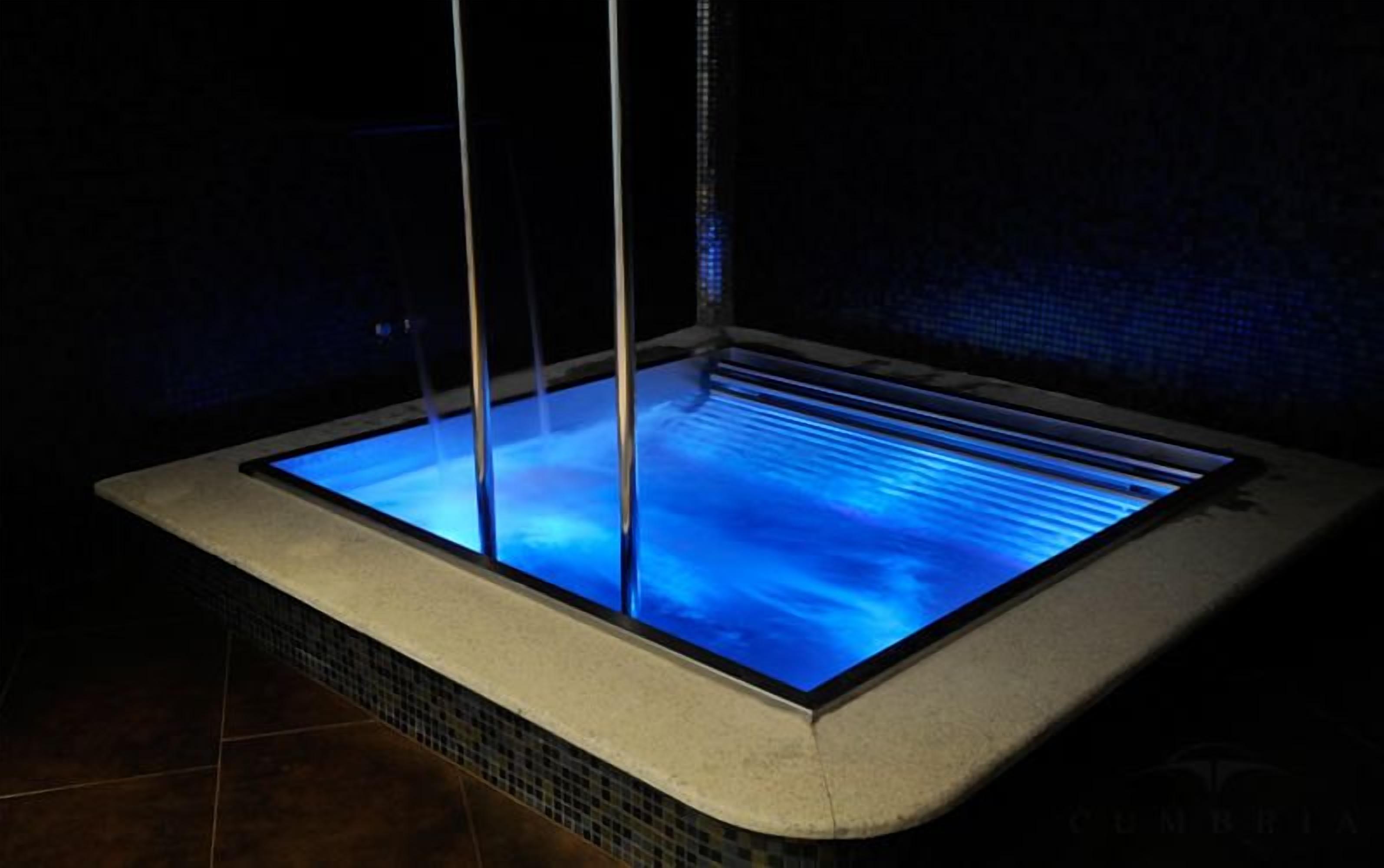 Tinaco rectangular con fondo de vidrio, rodeado de piso y paredes de azulejos.
