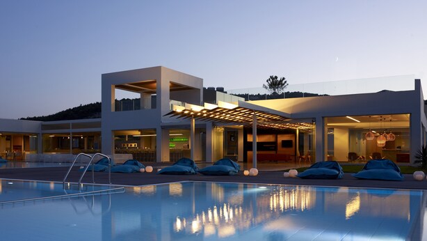Un hotel moderno con piscina, terraza al aire libre y una entrada bien iluminada.