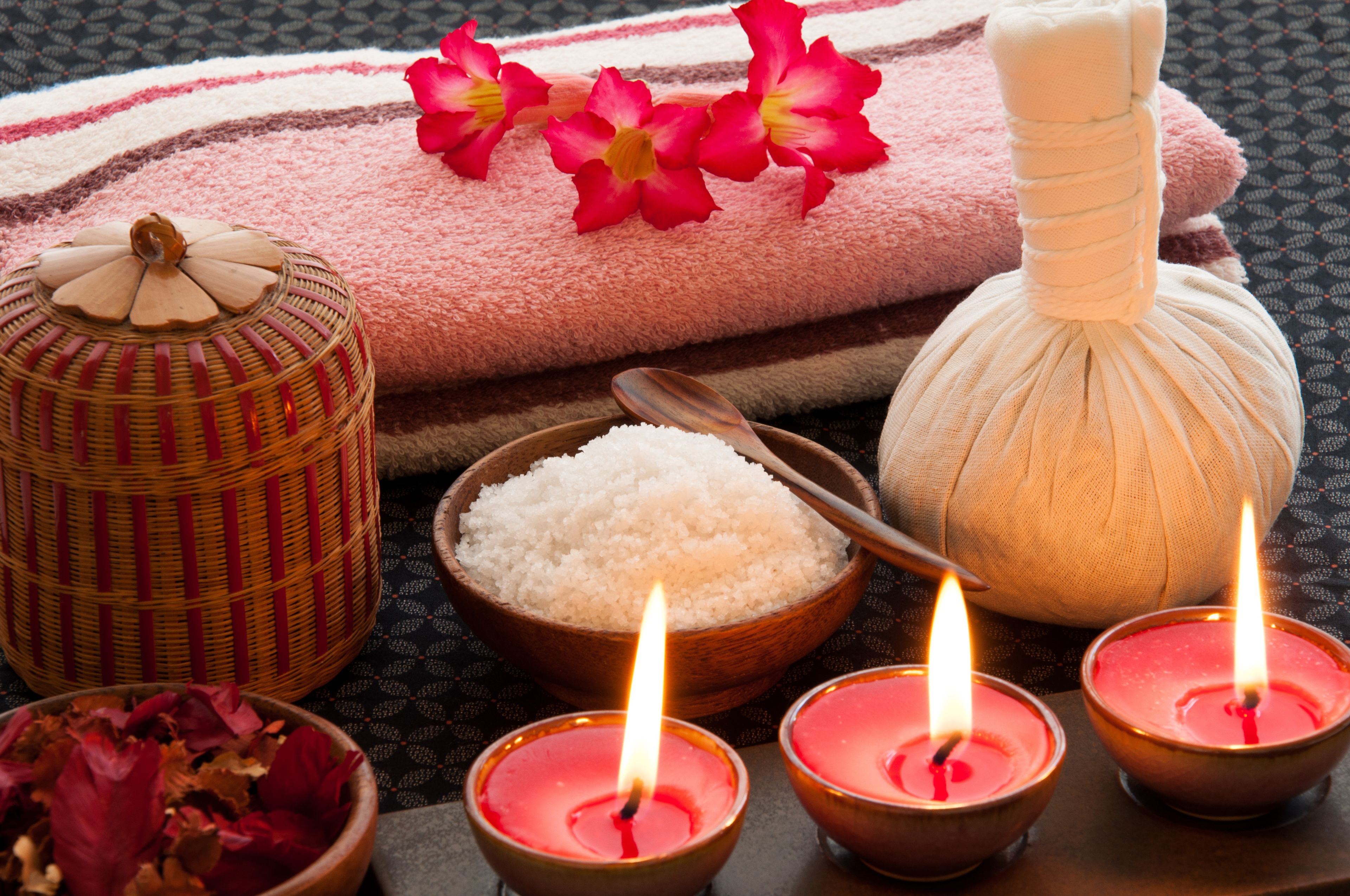 Un décor de spa avec une serviette, une pierre de massage, un bol de riz et des bougies.