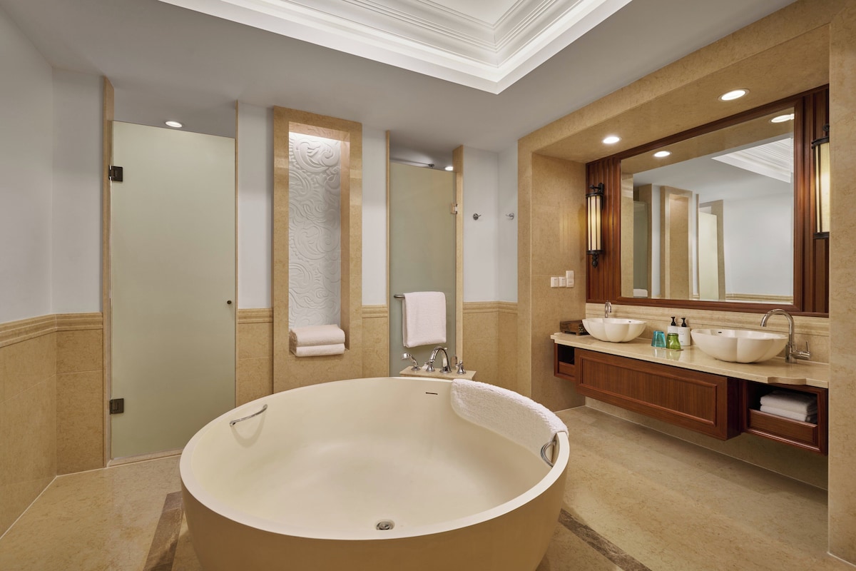 A modern bathroom with a freestanding bathtub, a large mirror, and a vanity with a sink.