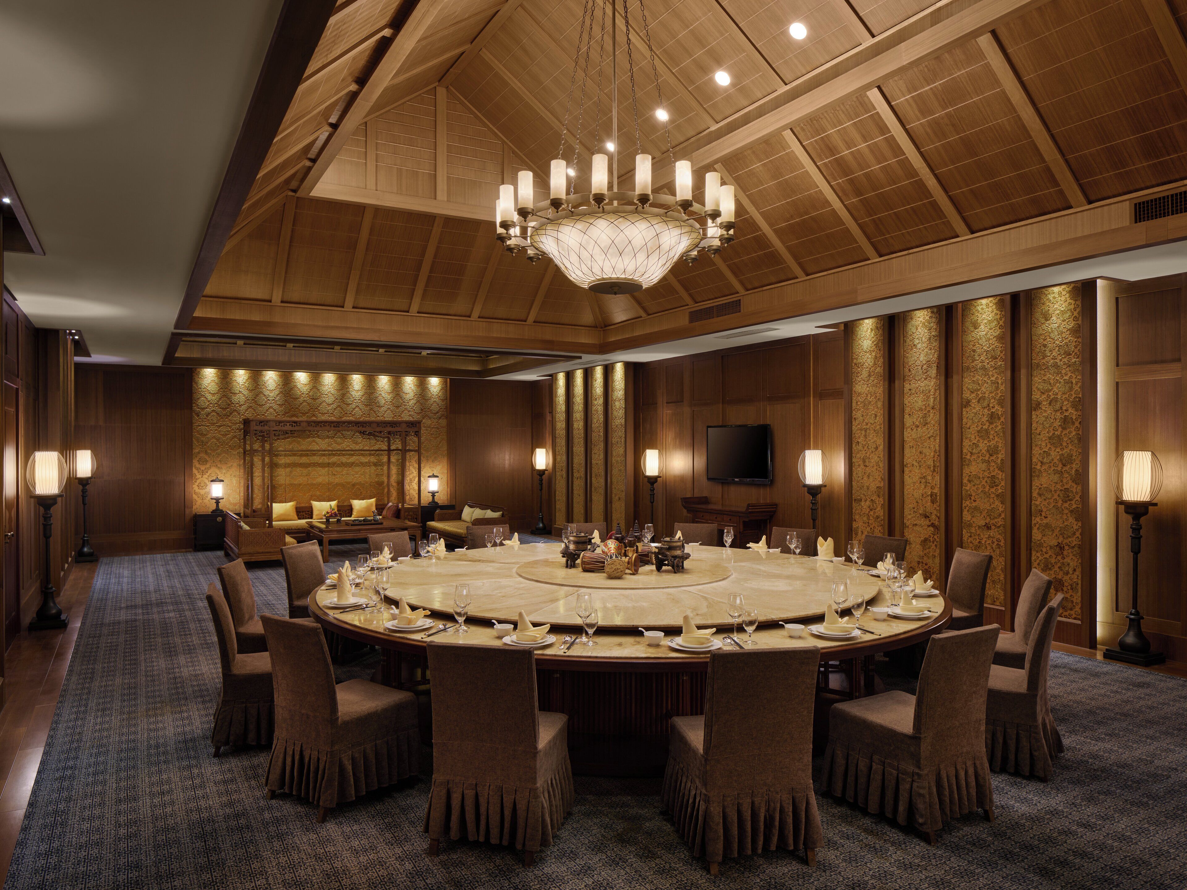 A large conference room with a round table, multiple chairs, and a chandelier.