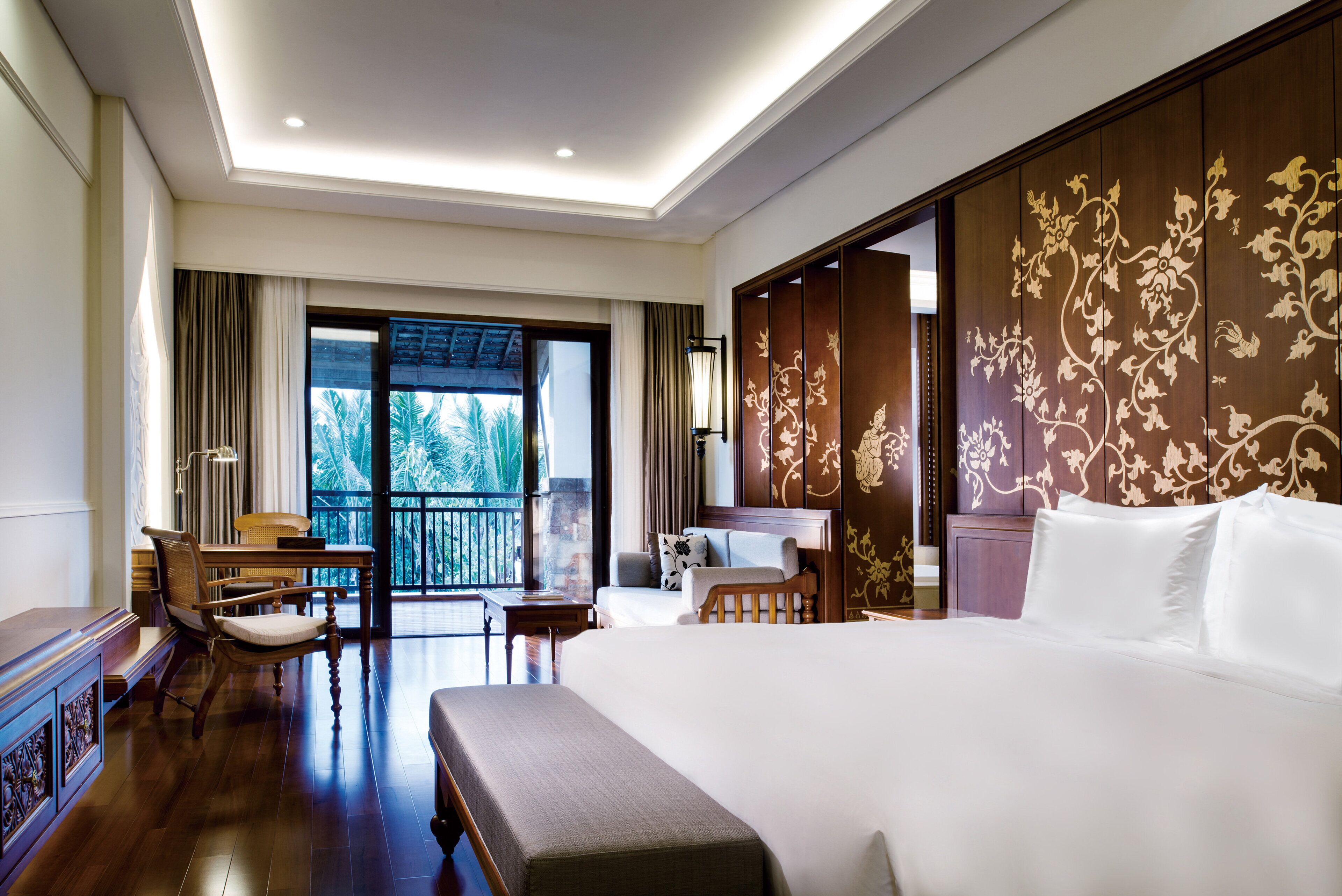 A hotel room with a large bed, a desk, a chair, and a view of the outdoors.