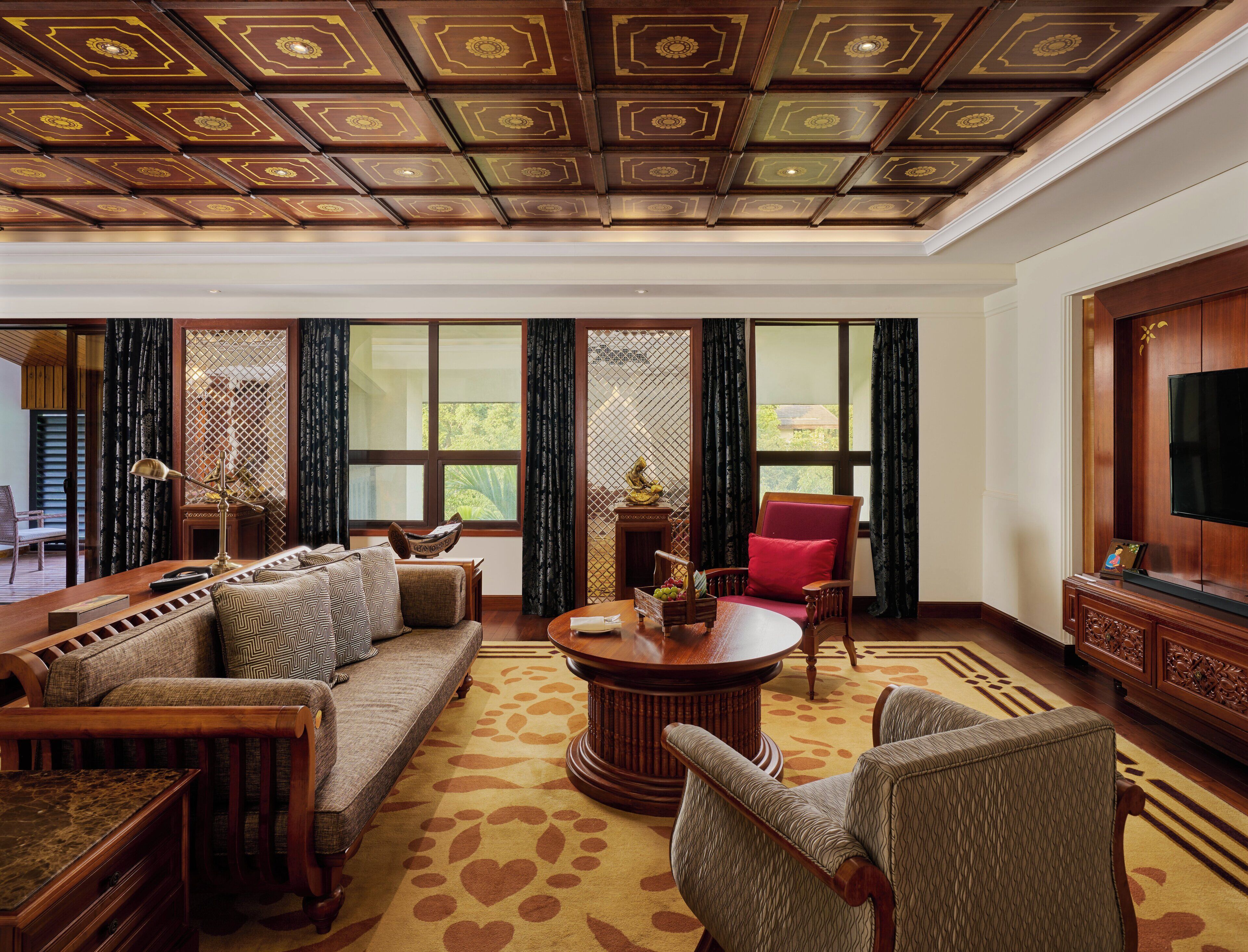 A spacious living room with a high ceiling, large windows, and a comfortable seating area.