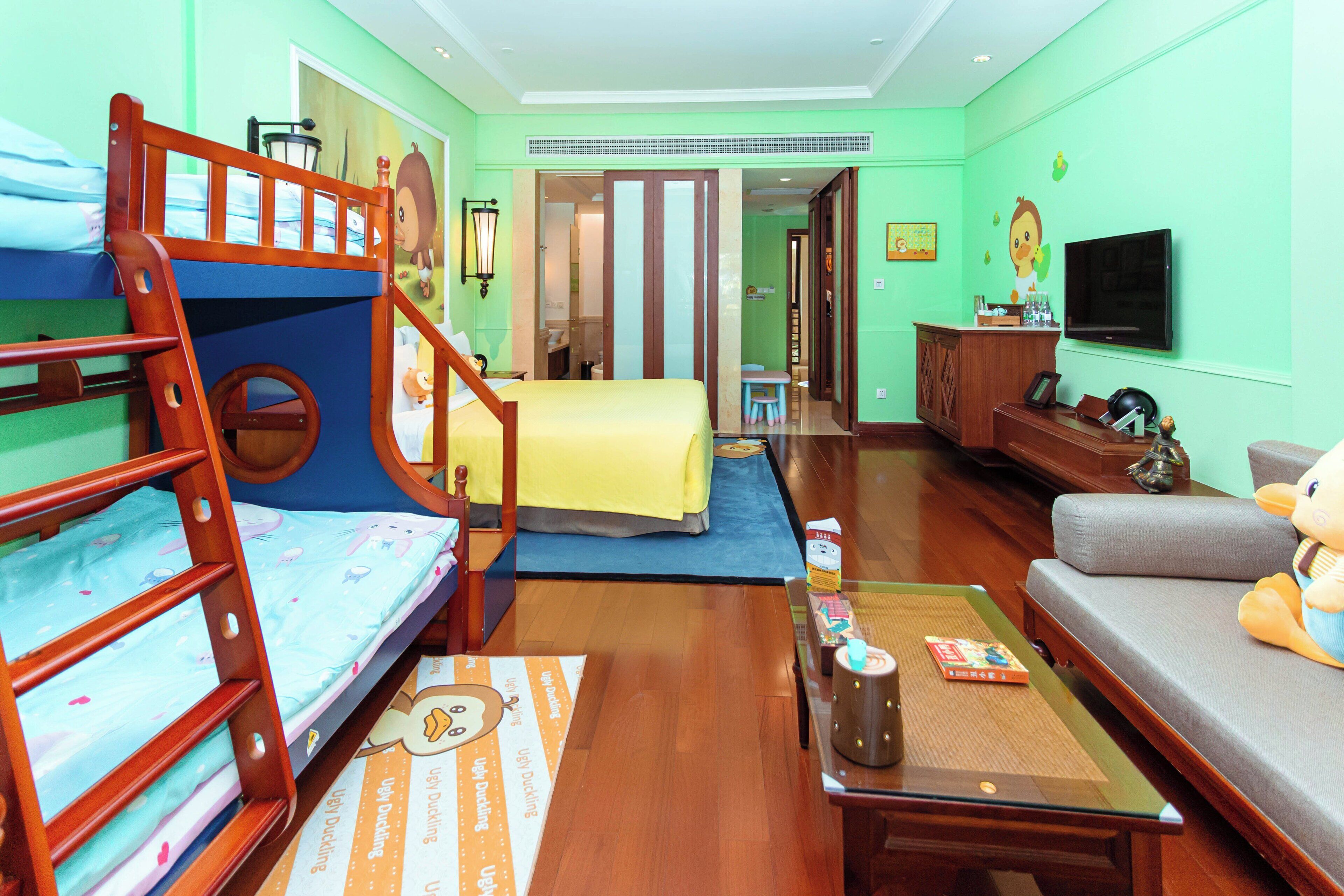 A child-friendly room with bunk beds, a sofa, a TV, and a desk.