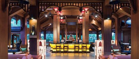 A lobby with a reception desk, seating area, and decorative elements like lanterns and columns.