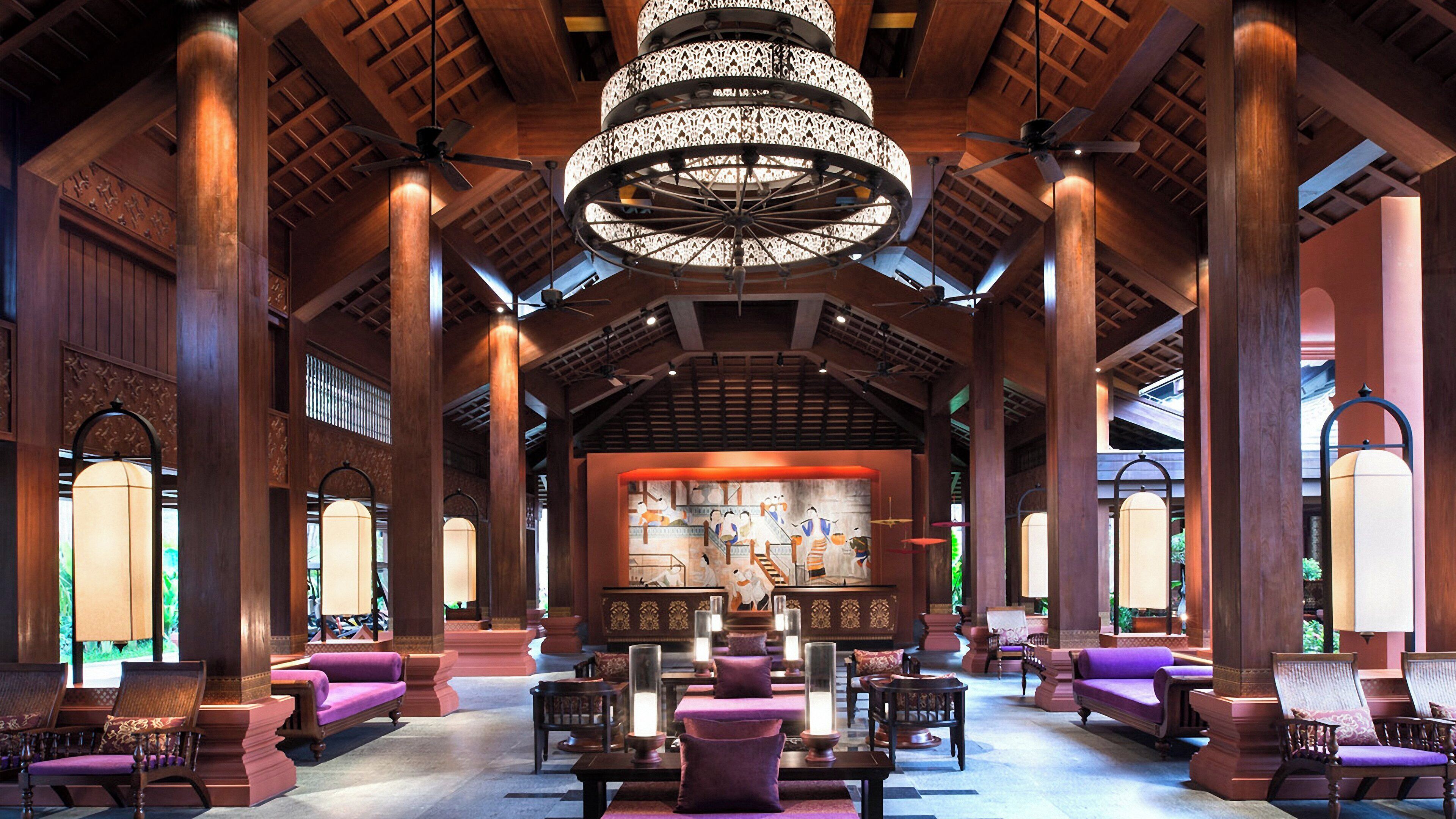 A spacious lobby with high wooden ceilings, large chandeliers, and comfortable seating areas.