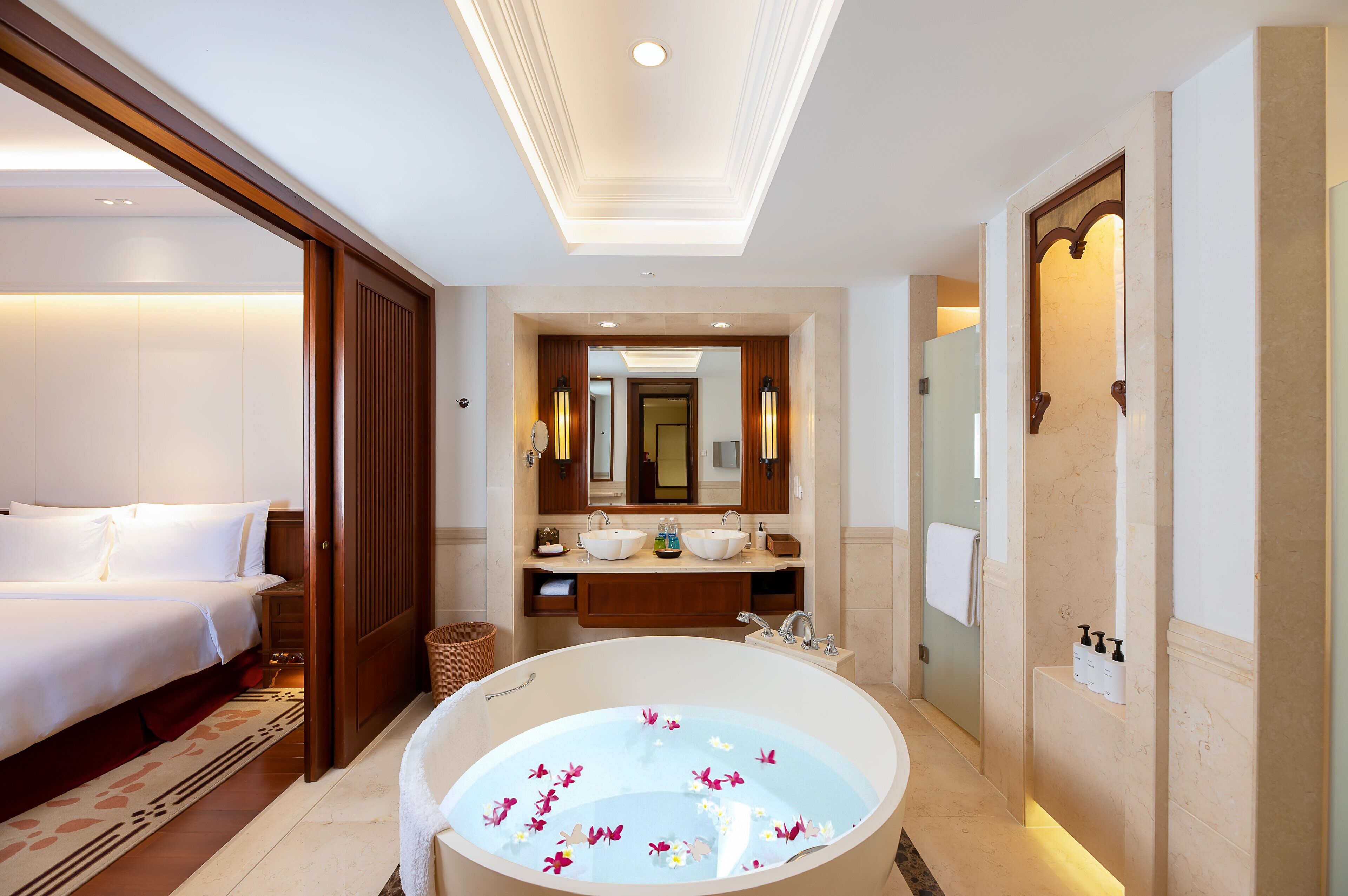 A hotel room with a large bed, a bathroom with a bathtub, and a mirror above the sink.
