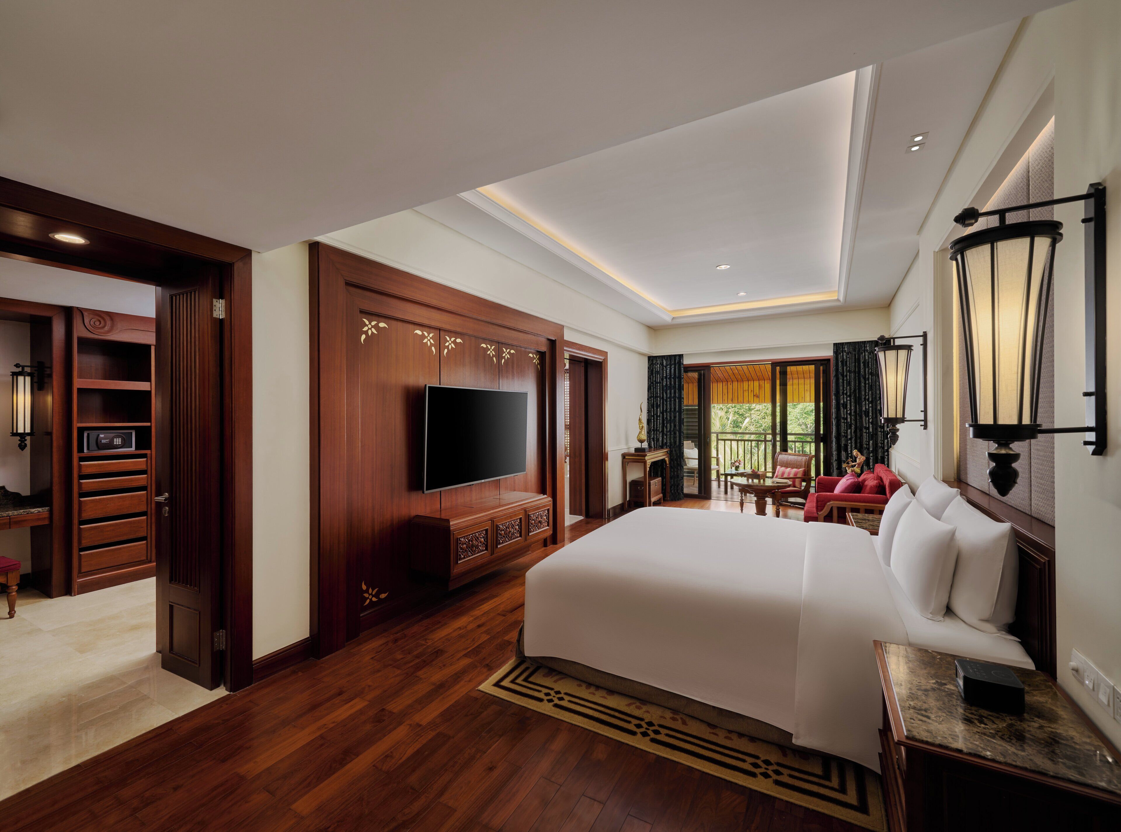 A hotel room with a large bed, a flat-screen TV, a wooden cabinet, and a balcony with a view.