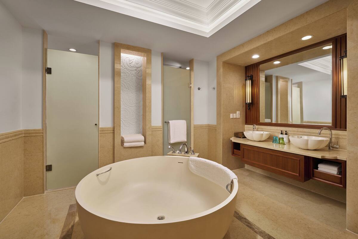 A modern bathroom with a freestanding bathtub, a large mirror, and a vanity with a sink.