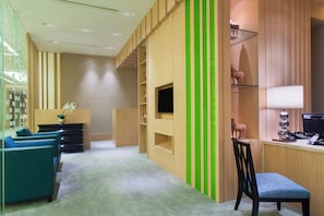 Un interior moderno con una recepción, zona de estar y un televisor montado en un panel de madera.