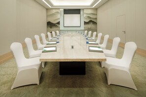 A conference room with a long table, white chairs, and a projector screen. - Holiday Inn Nanyang by IHG (Nanyang)